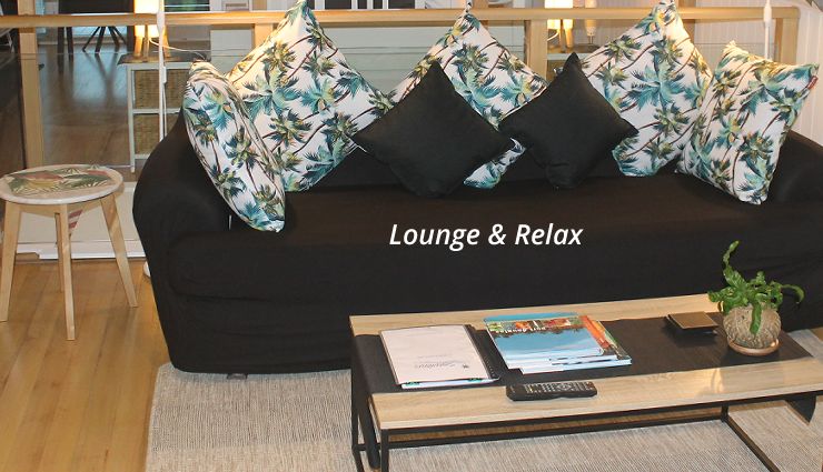 Open plan studio interior featuring high ceilings, lounge area, kitchenette, and private deck access
