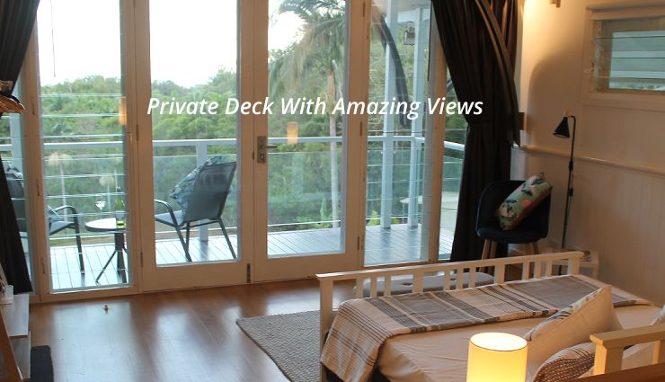 Private timber balcony deck with panoramic tropical views at Oak Beach accommodation